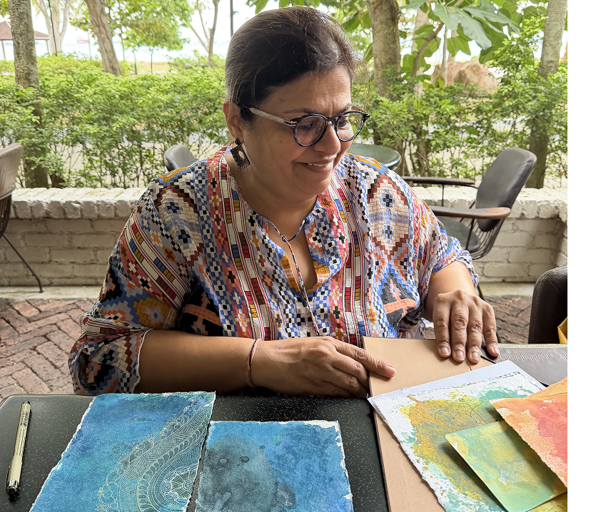 Preetie Kohli, the artist behind Tangled Monk, painting at her worktable