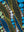 Close-up of stippled olive and blue reeds with rows of small white and sage dots rising between them — Tangled Monk original hand-drawn art